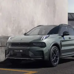 Un elegante SUV Lynk & Co 01 en color verde oscuro, aparcado junto a un muro de hormigón.