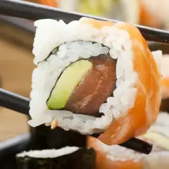 Palillos sostienen un rollo de sushi con salmón y aguacate. ¡Cuidado, el sushi engorda si no te controlas!