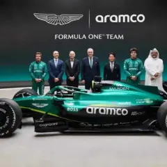 El nuevo Aston Martin F1, un coche verde brillante, posa junto a pilotos y directivos.