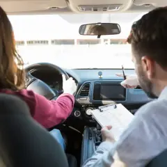Instructor de autoescuela revisa notas mientras enseña a conducir. ¿Cuánto gana un profesor de autoescuela?