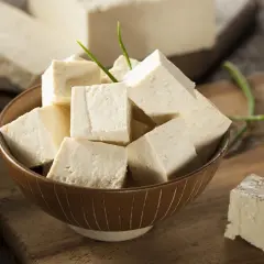 Tofu en cubos en un tazón, con bloques enteros al fondo. Aunque dicen que el tofu engorda, es un alimento versátil.