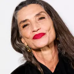 Mujer mayor con labios rojos vibrantes y cabello largo y oscuro. Un ejemplo de cómo maquillarse a los 60, resaltando la belleza madura.
