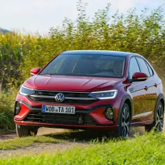 El Volkswagen Taigo rojo circula por un camino polvoriento, quizás enfrentando algunos problemas de tracción en el campo.