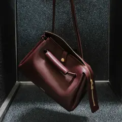 Bolso Loewe de cuero burdeos, con detalles dorados y el logo grabado. Un accesorio que evoca el lujo y la artesanía de España, de donde es Loewe.