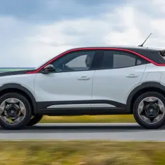 Opel Mokka blanco con detalles rojos, conduciendo por la costa. Las opiniones sobre este coche son muy positivas.
