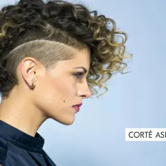 Mujer con pelo corto rizado y rapado asimétrico. Un estilo audaz que resalta su personalidad.