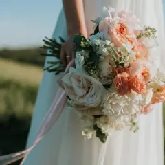 Novia con ramo de flores en tonos pastel, la última tendencia en ramos de novia, con cintas rosas cayendo.