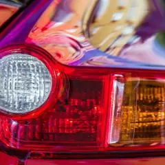Detalle de un piloto trasero de coche rojo. Se aprecia el catadióptrico, que es un elemento reflectante de seguridad.