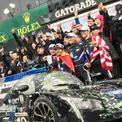 Fernando Alonso celebra la victoria en Daytona con su equipo, cubiertos de confeti y con banderas.
