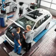 Técnicos revisan el motor de un coche de gasolina en un taller. El mantenimiento del coche es esencial.