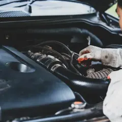 Mecánico revisa motor, buscando remedios caseros para quitar la carbonilla del coche.