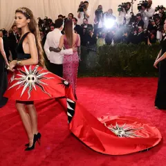 Zendaya deslumbrante en la Met Gala con un vestido rojo solar y una larga cola.