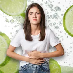 Mujer con cara de dolor, sujetándose el abdomen, rodeada de rodajas de limón y burbujas. ¿Será que el limón estriñe?