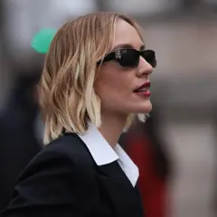 Mujer con melena corta rubia, gafas de sol y traje negro. Cortes de pelo melena corta modernos y chic.