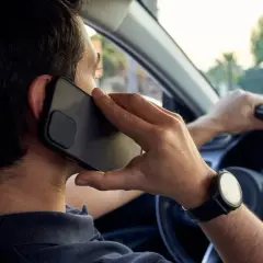 Hombre hablando por teléfono mientras conduce, una acción que puede llevar a conducir de forma temeraria.