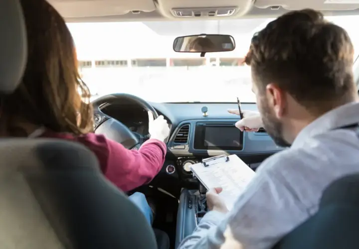 Instructor de autoescuela revisa notas mientras enseña a conducir. ¿Cuánto gana un profesor de autoescuela?