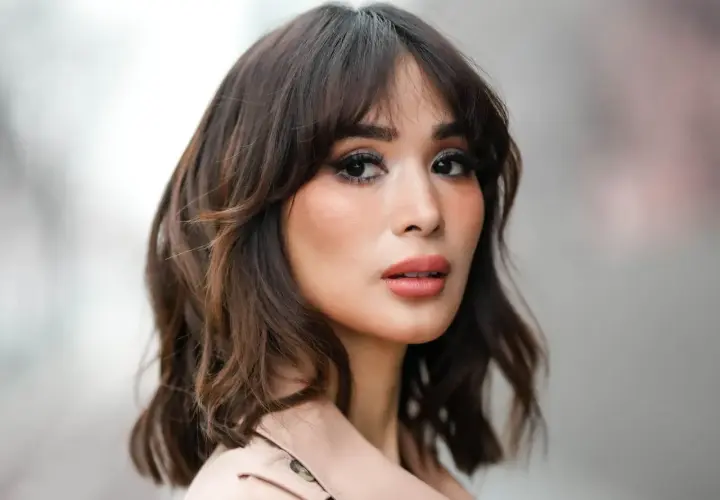 Mujer con un moderno corte wolf cut, cabello castaño ondulado y maquillaje llamativo.