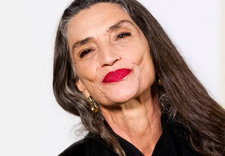 Mujer mayor con labios rojos vibrantes y cabello largo y oscuro. Un ejemplo de cómo maquillarse a los 60, resaltando la belleza madura.