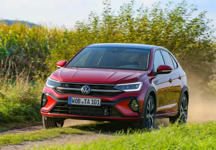 El Volkswagen Taigo rojo circula por un camino polvoriento, quizás enfrentando algunos problemas de tracción en el campo.