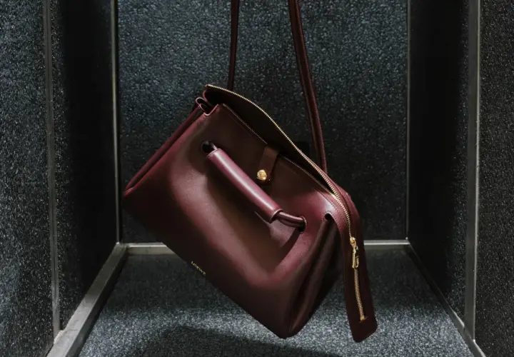 Bolso Loewe de cuero burdeos, con detalles dorados y el logo grabado. Un accesorio que evoca el lujo y la artesanía de España, de donde es Loewe.