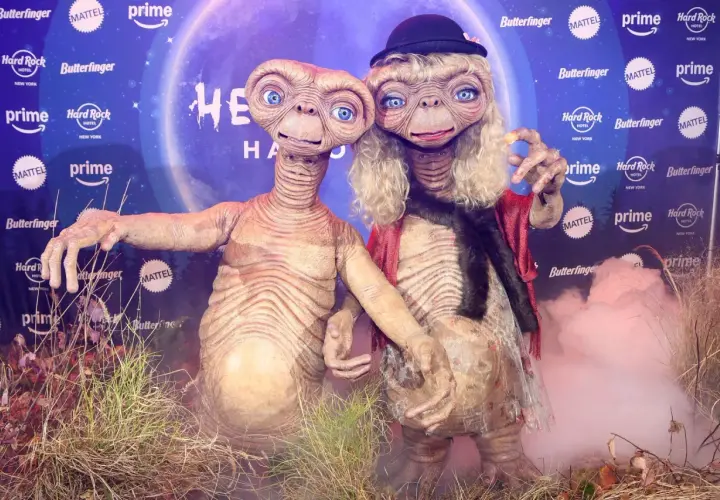 Dos E.T. disfrazados, uno con sombrero y peluca rubia, celebran Halloween. ¡Un guiño a Heidi Klum!
