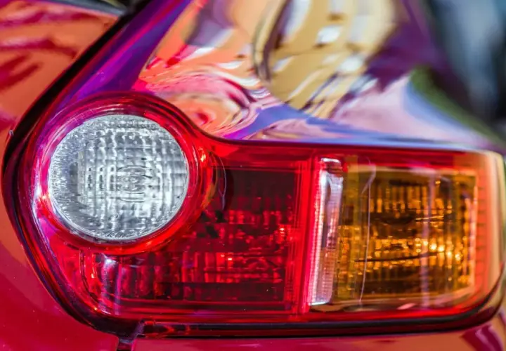 Detalle de un piloto trasero de coche rojo. Se aprecia el catadióptrico, que es un elemento reflectante de seguridad.