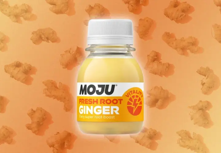 Botella de MOJU Fresh Root Ginger, destacando sus ginger shot beneficios. Fondo naranja con trozos de jengibre.