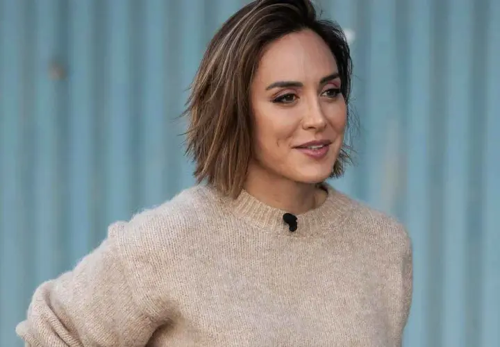 Mujer con un moderno corte de pelo bob, luciendo un suéter beige y una sonrisa amable.