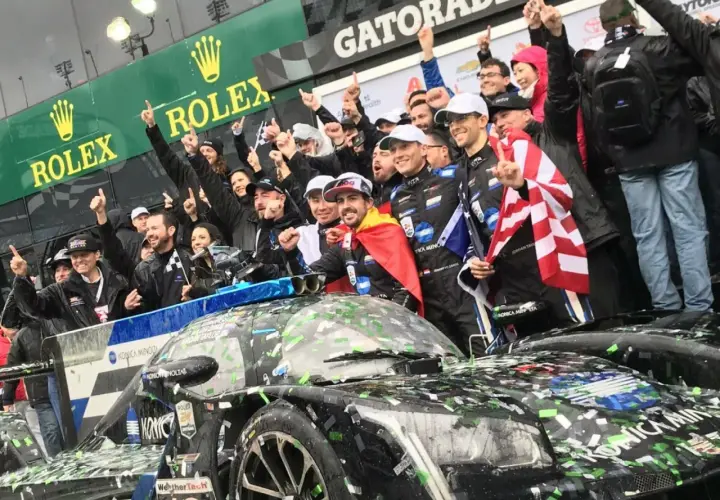 Fernando Alonso celebra la victoria en Daytona con su equipo, cubiertos de confeti y con banderas.