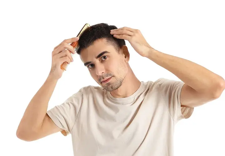Hombre peinando su cabello, preocupado por en qué época se cae más el pelo.
