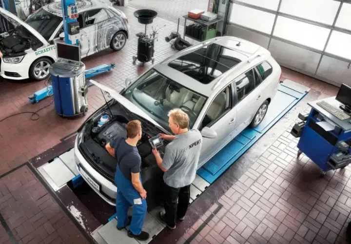 Técnicos revisan el motor de un coche de gasolina en un taller. El mantenimiento del coche es esencial.