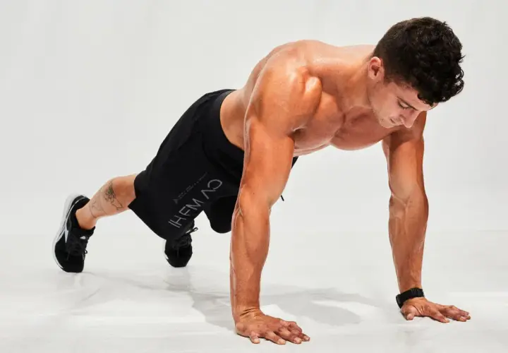 Hombre haciendo flexiones en posición de plancha, listo para un entrenamiento de hiit en casa.