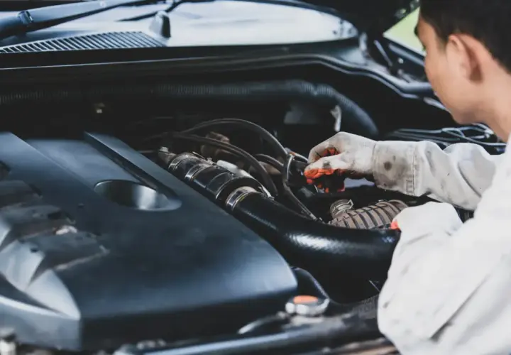 Mecánico revisa motor, buscando remedios caseros para quitar la carbonilla del coche.