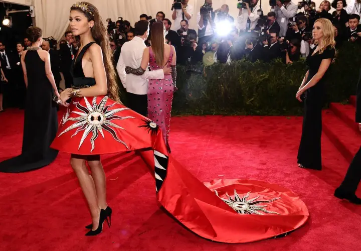 Zendaya deslumbrante en la Met Gala con un vestido rojo solar y una larga cola.
