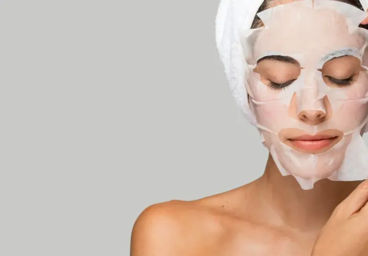 Mujer aplicándose mascarillas hidratantes pelo, con toalla en la cabeza.