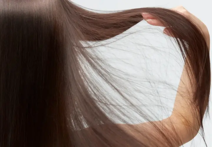 Detalle de pelo fino y escaso de mujer, con mechones sueltos que caen sobre su brazo.