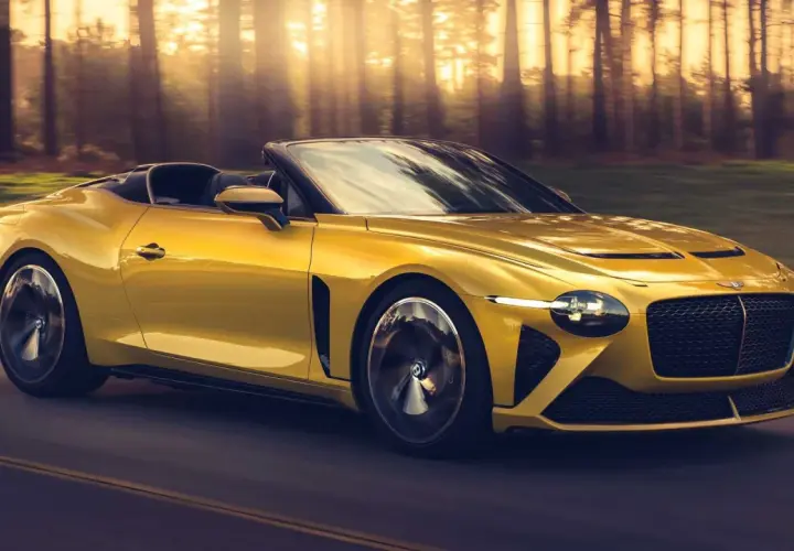 Un Bentley Mulliner Bacalar amarillo brillante recorre un camino boscoso al atardecer, con los rayos del sol filtrándose entre los árboles.