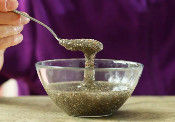 Cuchara levanta una porción gelatinosa de agua de chía de un cuenco de vidrio.