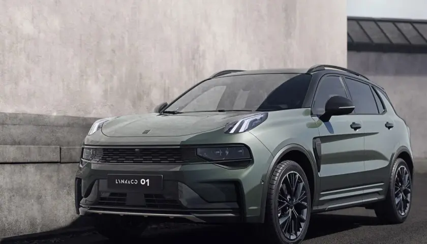 Un elegante SUV Lynk & Co 01 en color verde oscuro, aparcado junto a un muro de hormigón.