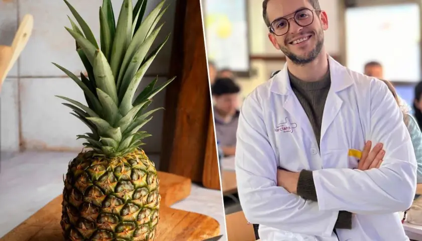 Un hombre sonriente con bata blanca y una piña entera en una tabla de cortar. ¿Será que la piña por la noche adelgaza?