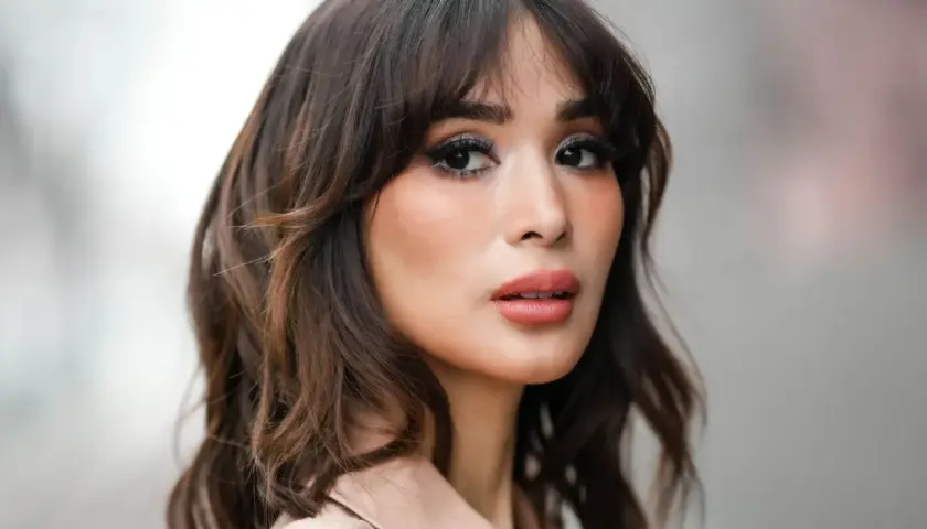 Mujer con un moderno corte wolf cut, cabello castaño ondulado y maquillaje llamativo.