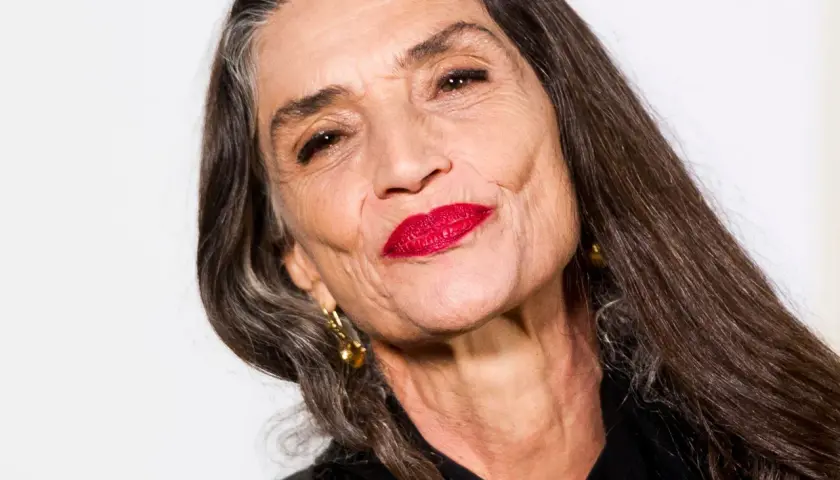 Mujer mayor con labios rojos vibrantes y cabello largo y oscuro. Un ejemplo de cómo maquillarse a los 60, resaltando la belleza madura.