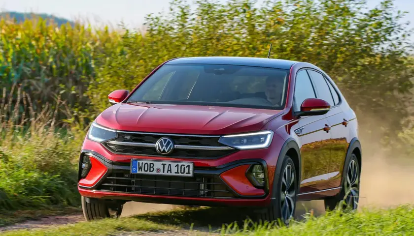 El Volkswagen Taigo rojo circula por un camino polvoriento, quizás enfrentando algunos problemas de tracción en el campo.