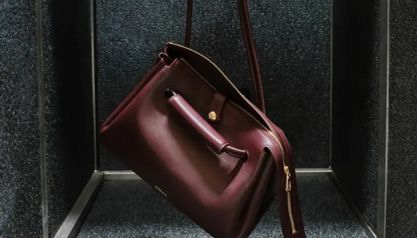 Bolso Loewe de cuero burdeos, con detalles dorados y el logo grabado. Un accesorio que evoca el lujo y la artesanía de España, de donde es Loewe.