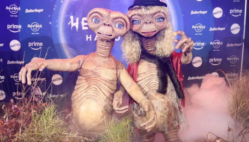 Dos E.T. disfrazados, uno con sombrero y peluca rubia, celebran Halloween. ¡Un guiño a Heidi Klum!