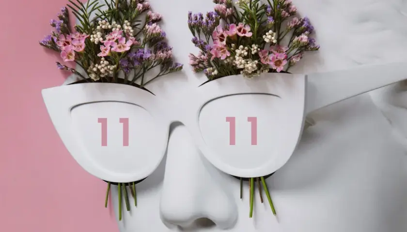 Busto blanco con flores rosas y moradas brotando de unas gafas que muestran **11:11 hora espejo**.