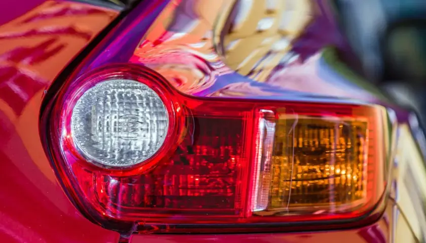 Detalle de un piloto trasero de coche rojo. Se aprecia el catadióptrico, que es un elemento reflectante de seguridad.