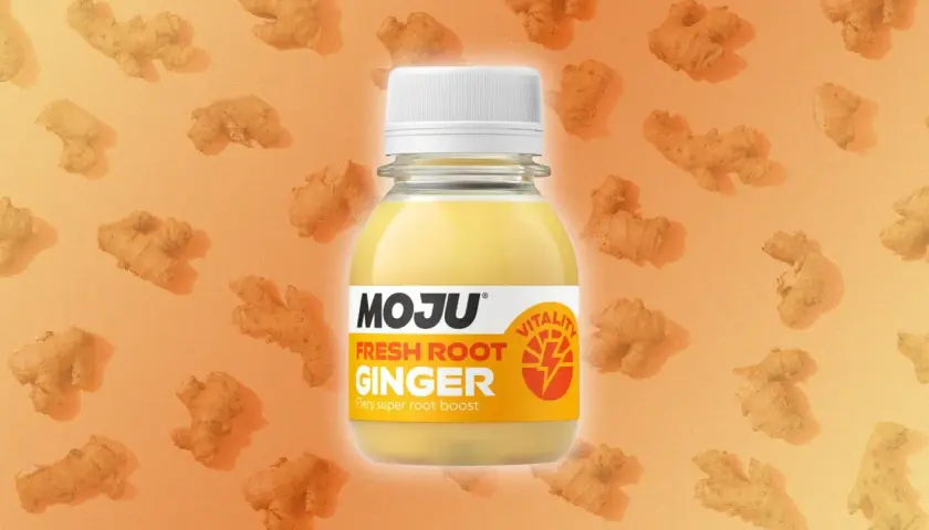 Botella de MOJU Fresh Root Ginger, destacando sus ginger shot beneficios. Fondo naranja con trozos de jengibre.