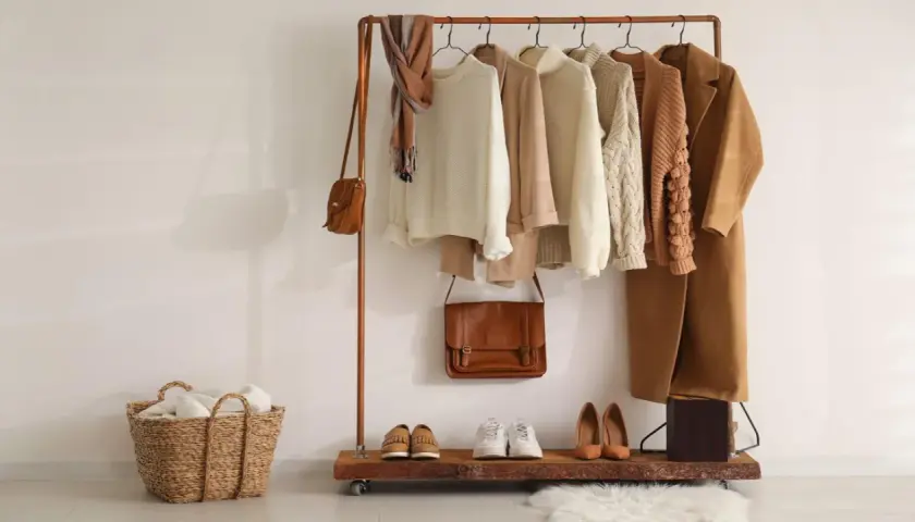 Un armario cápsula con prendas de punto, abrigos y bolsos en tonos tierra. Un ejemplo de cómo organizar tu ropa de forma eficiente.