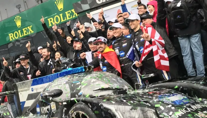 Fernando Alonso celebra la victoria en Daytona con su equipo, cubiertos de confeti y con banderas.